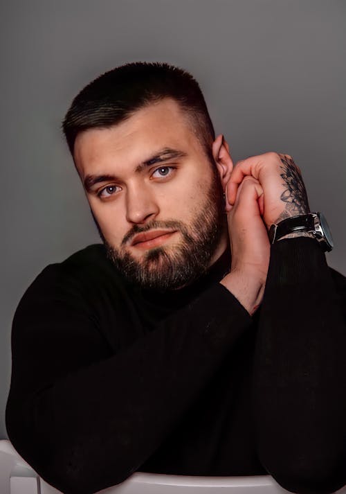 A Bearded Man in Black Long Sleeves Seriously Looking at the Camera