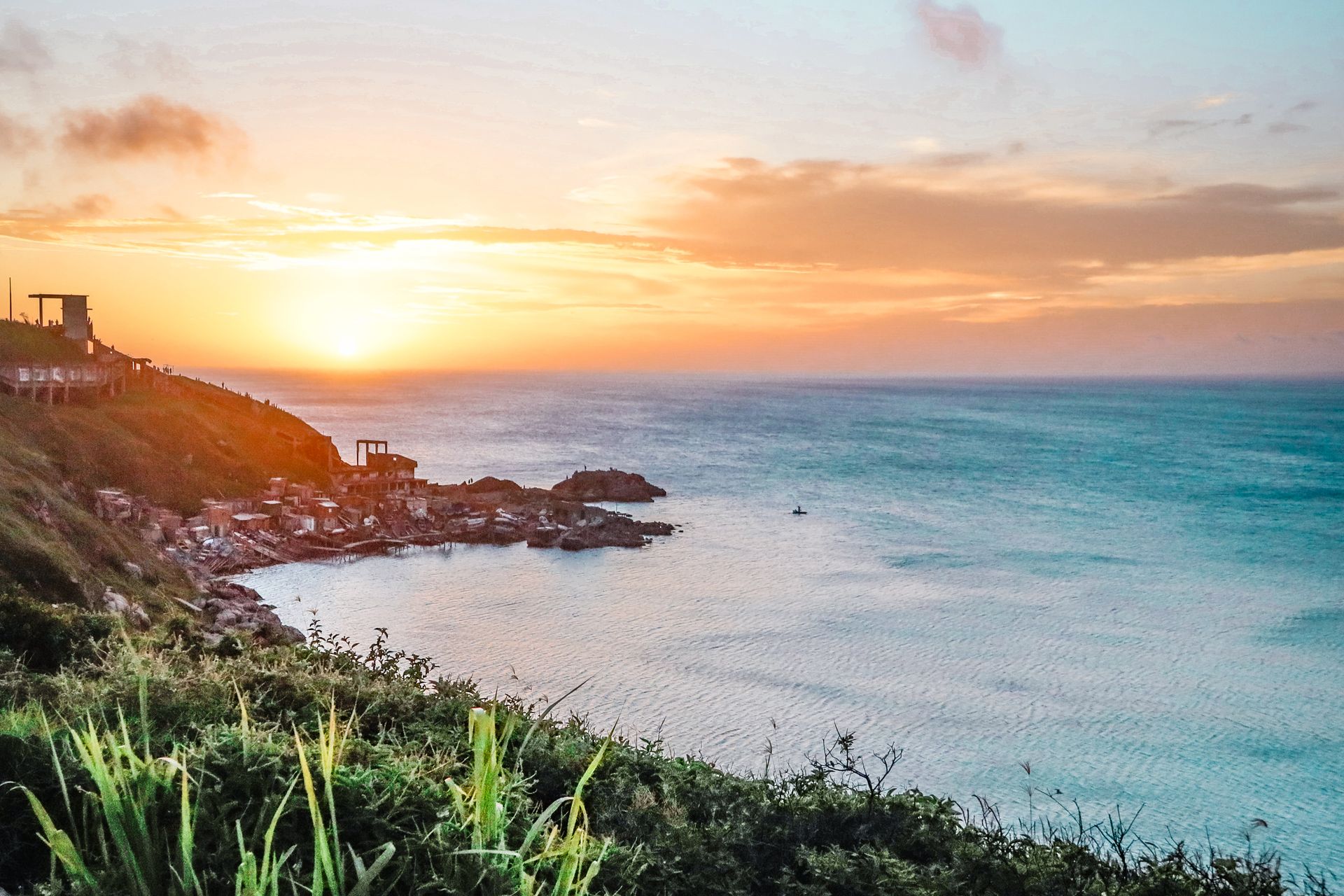 A breathtaking view of the ocean from a cliffside at sunrise with a vivid sky.