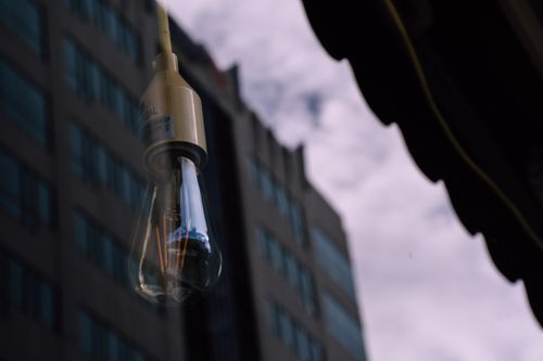 Free A glass bulb reflects the facade of a tall building, blending urban architecture with light. Stock Photo