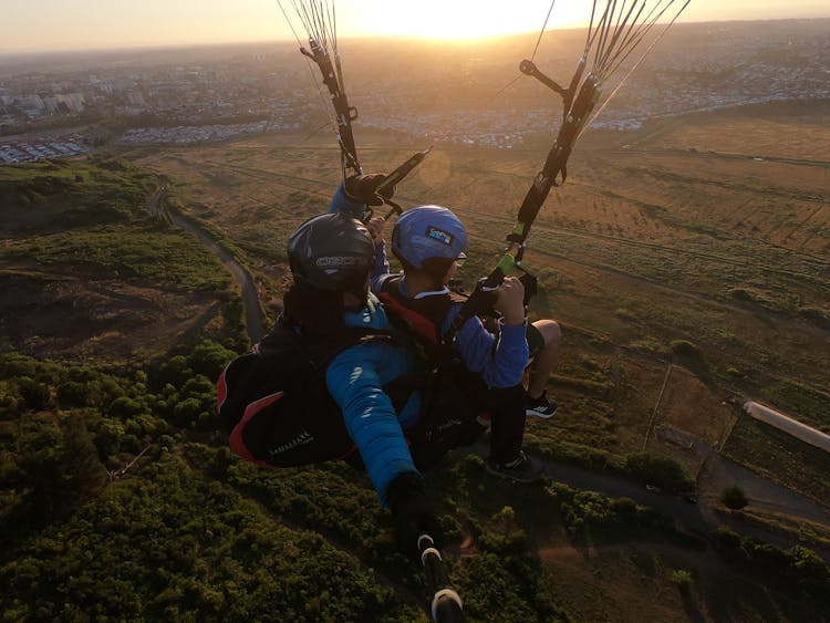 Two People Paragliding At Sunset 