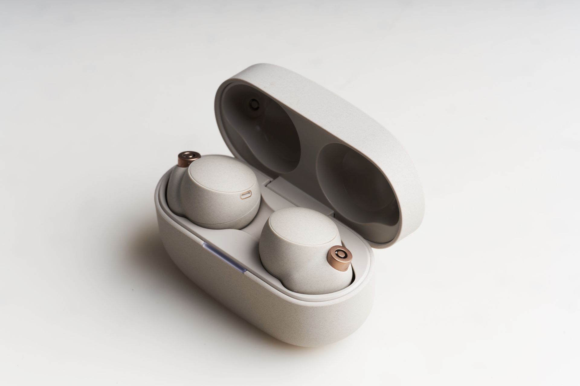Close-up of modern wireless earbuds in an open charging case on a plain background.