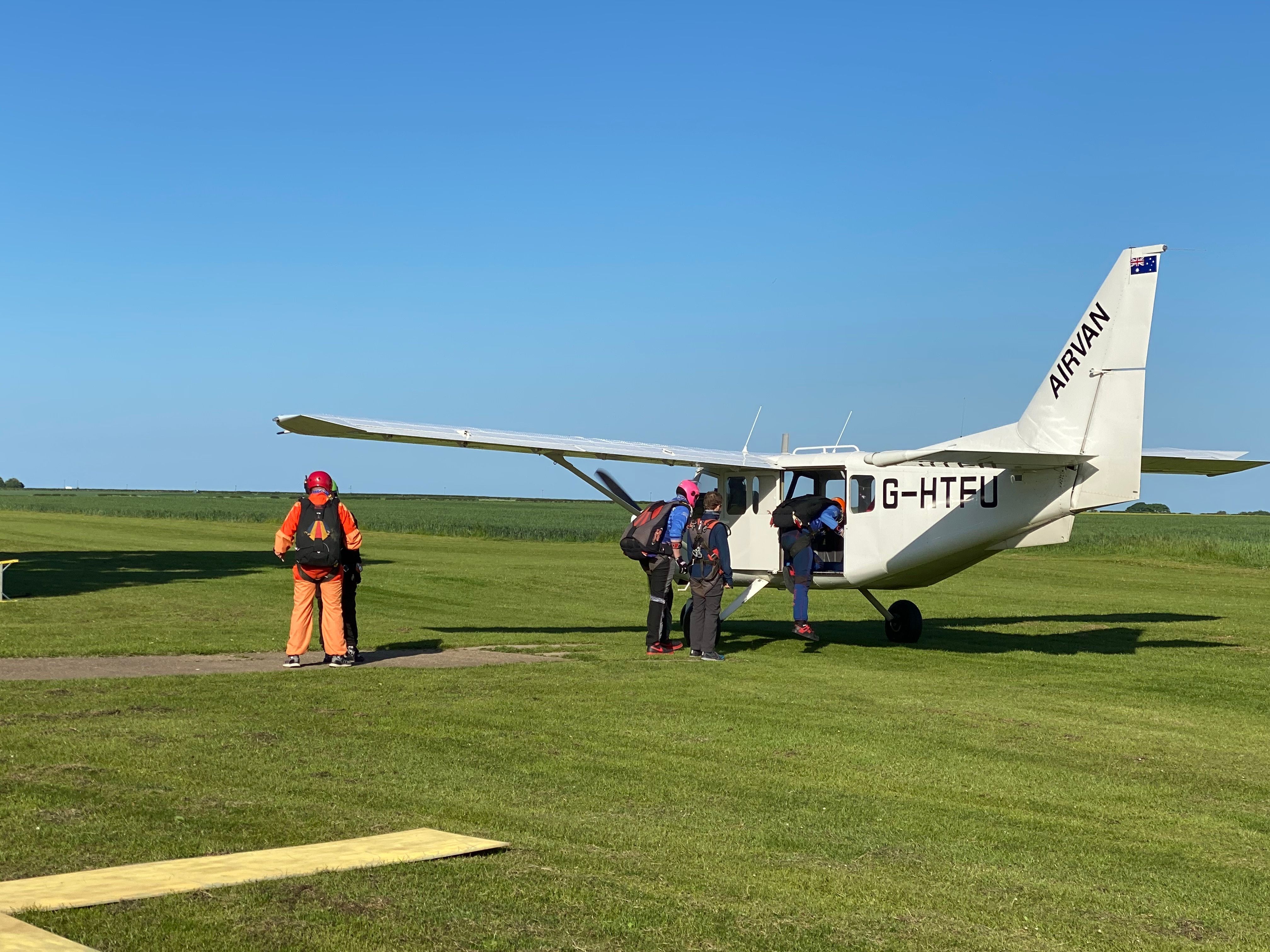 Skydivers preparing to board a small plane on a sunny day for an outdoor adventure.