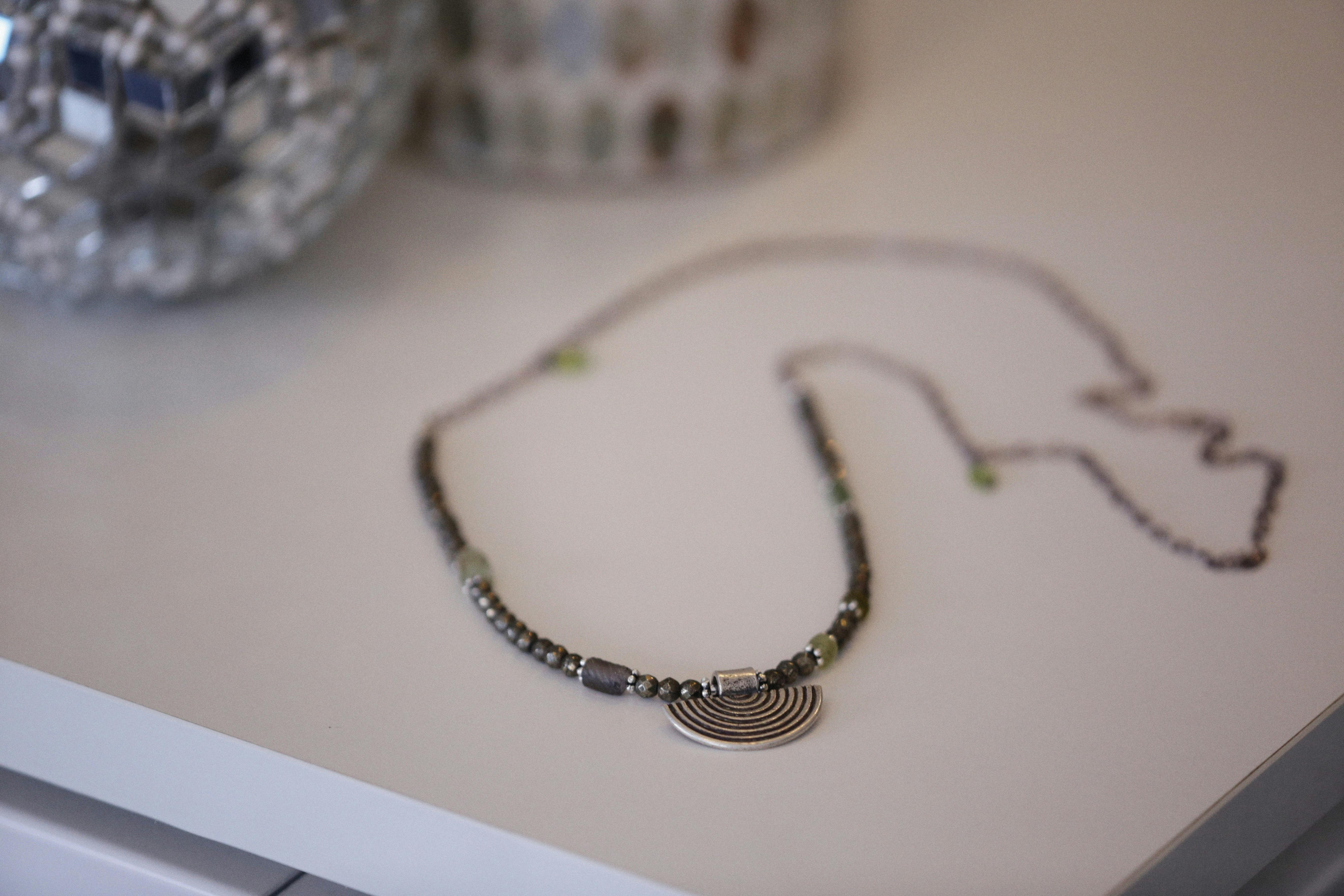 Close-up of a stylish beaded necklace with pendant on a white surface.