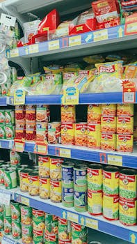 Canned and packaged goods neatly arranged on grocery store shelves, showcasing diverse food products.