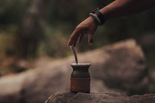 A person reaching for a traditional mate cup outdoors in Argentina.