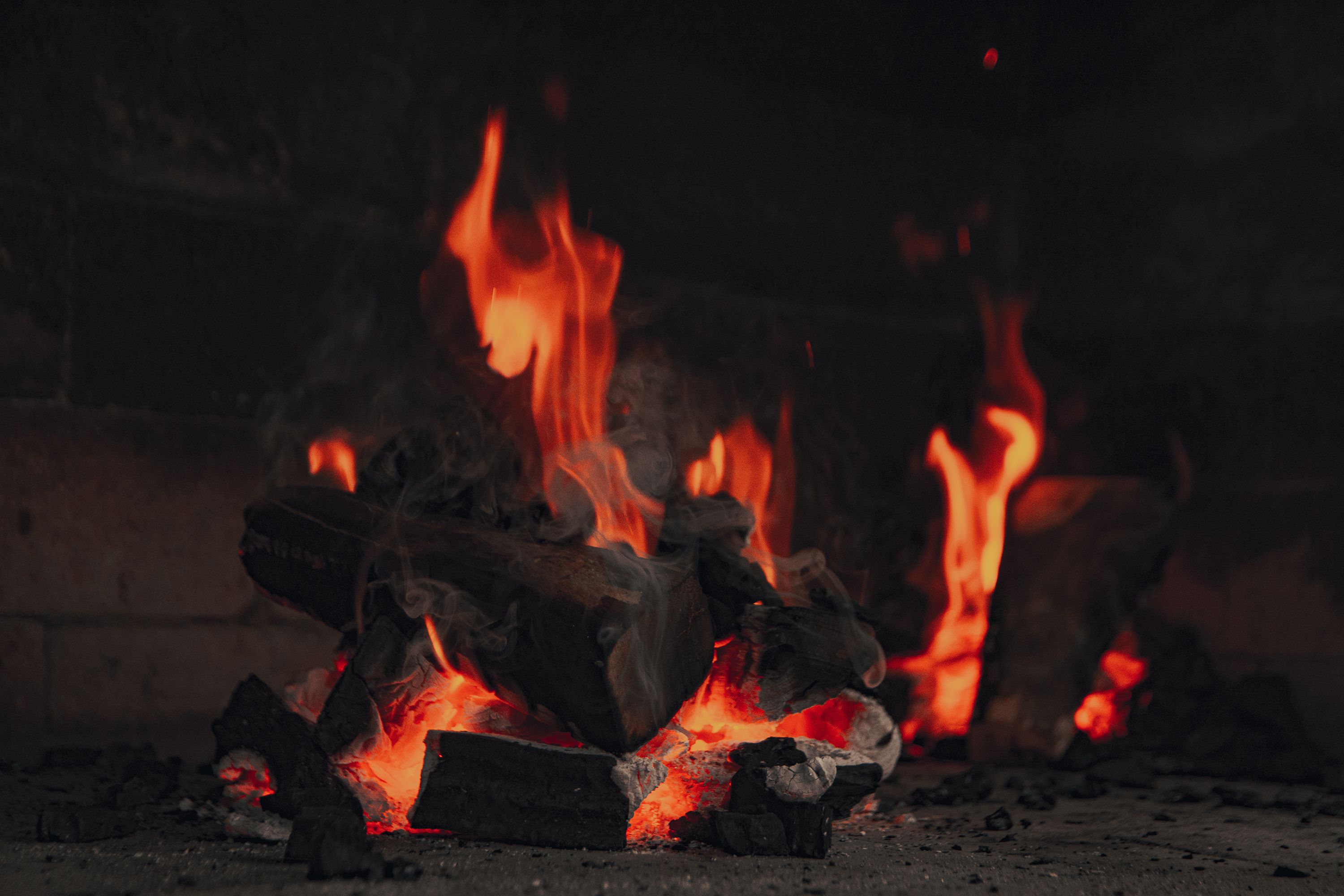 Close-up of burning firewood and glowing embers in a fireplace scene.