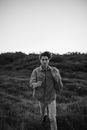 Young Man with Windblown Hair Walking Through Grasslands