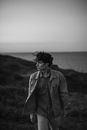 Young Man with Windblown Hair Walking in Meadow at Seaside 