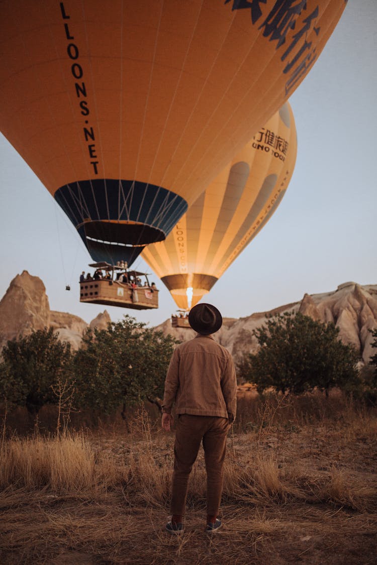 Two Balloons Landing On Prairie And Man Watching Them