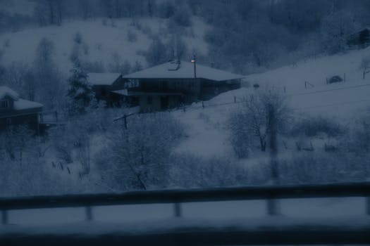 A serene snow-covered cabin nestled in a winter landscape captured at dusk, exuding tranquility and solitude.