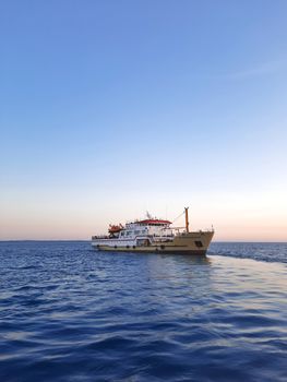 A tranquil scene of a ferry cruising on calm ocean waters during a beautiful sunset.