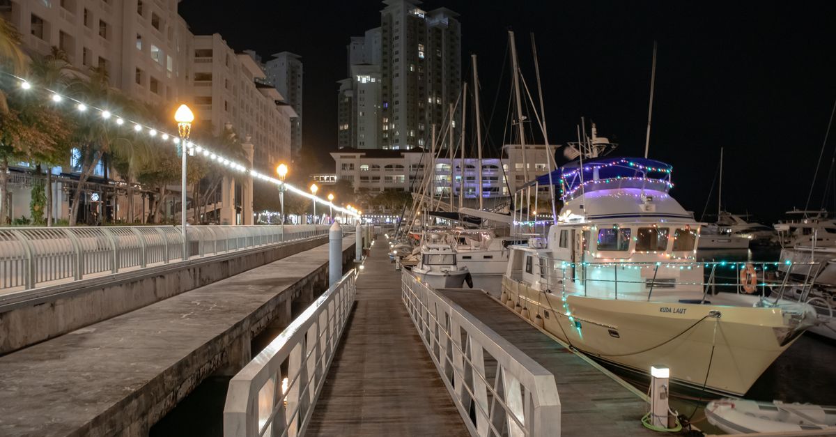 Illuminated marina with yachts docked in George Town, Malaysia at night.