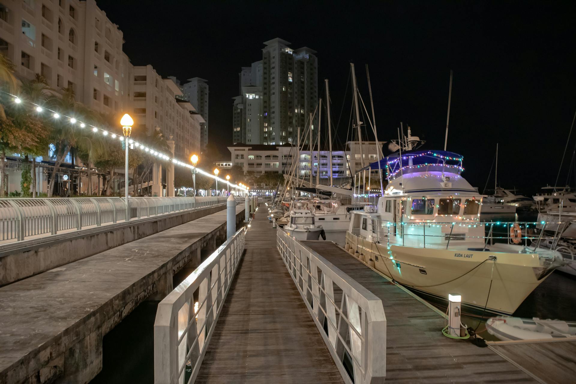 Illuminated marina with yachts docked in George Town, Malaysia at night.