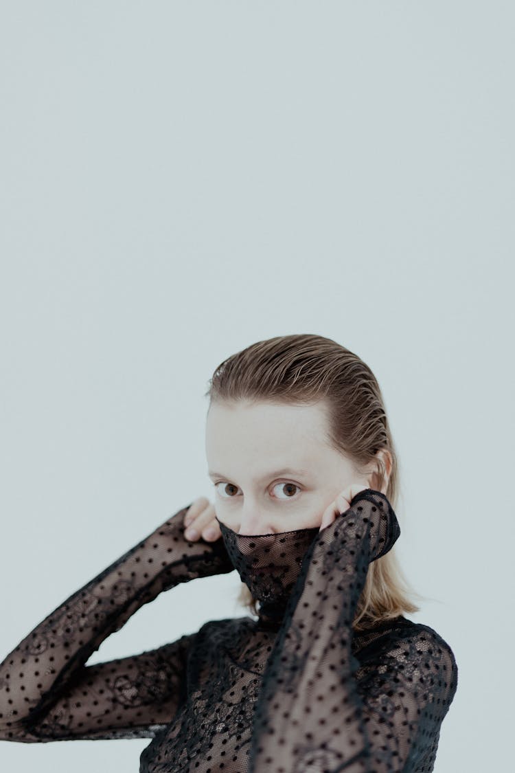 Blond Woman In Black Lace Shirt Covering Lower Part Of Face 