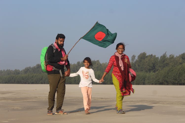 Family With A Bangladesh Flag Walking By The Beach 