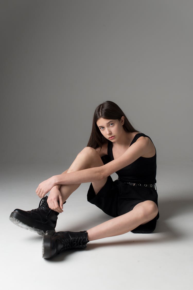 Teenage Girl With Long Black Hair In Sleeveless Top Shorts And Boots Sitting In Floor