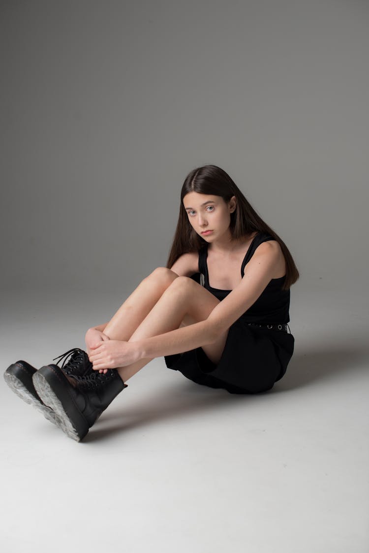Teenage Girl Wearing Black Top And Shorts Sitting On Floor