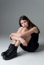 Teenage Girl with Long Black Hair Sitting on Floor and Looking Sadly at Camera