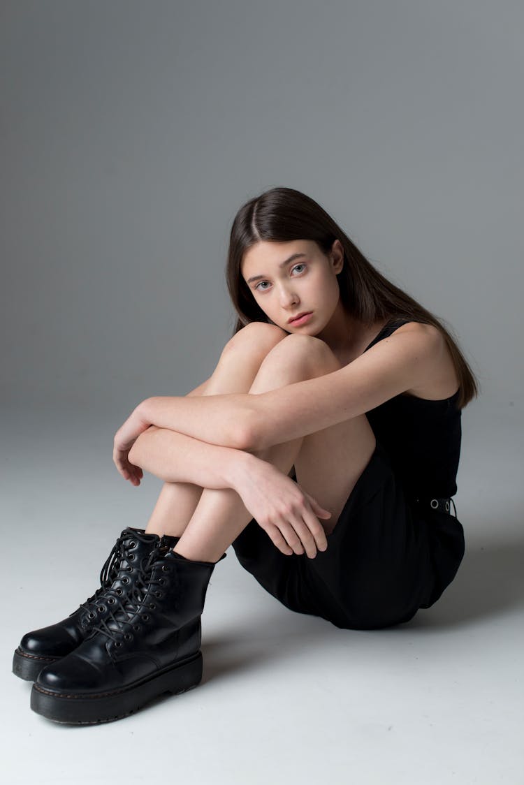 Teenage Girl With Long Black Hair Sitting On Floor And Looking Sadly At Camera