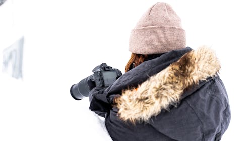 Back View of a Person in Winter Clothing Taking Photos Using DLSR Camera
