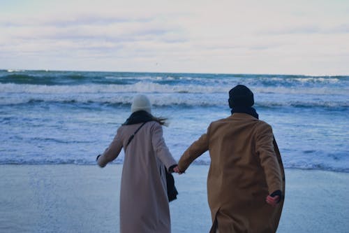 Backview of Couple running towards the Sea