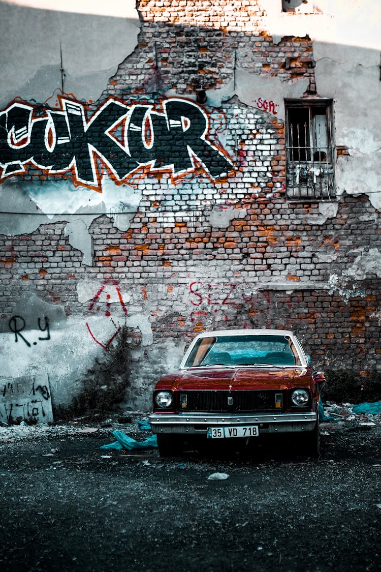 Vintage Car Parked Under Wall Covered In Graffiti