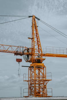 An imposing tower crane in Angola reaching into the cloudy sky, showcasing construction technology.