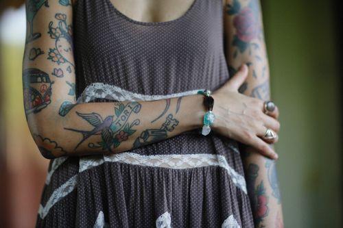 Free Close-up of fashionable tattooed arms adorned with bracelets and rings in summer dress. Stock Photo