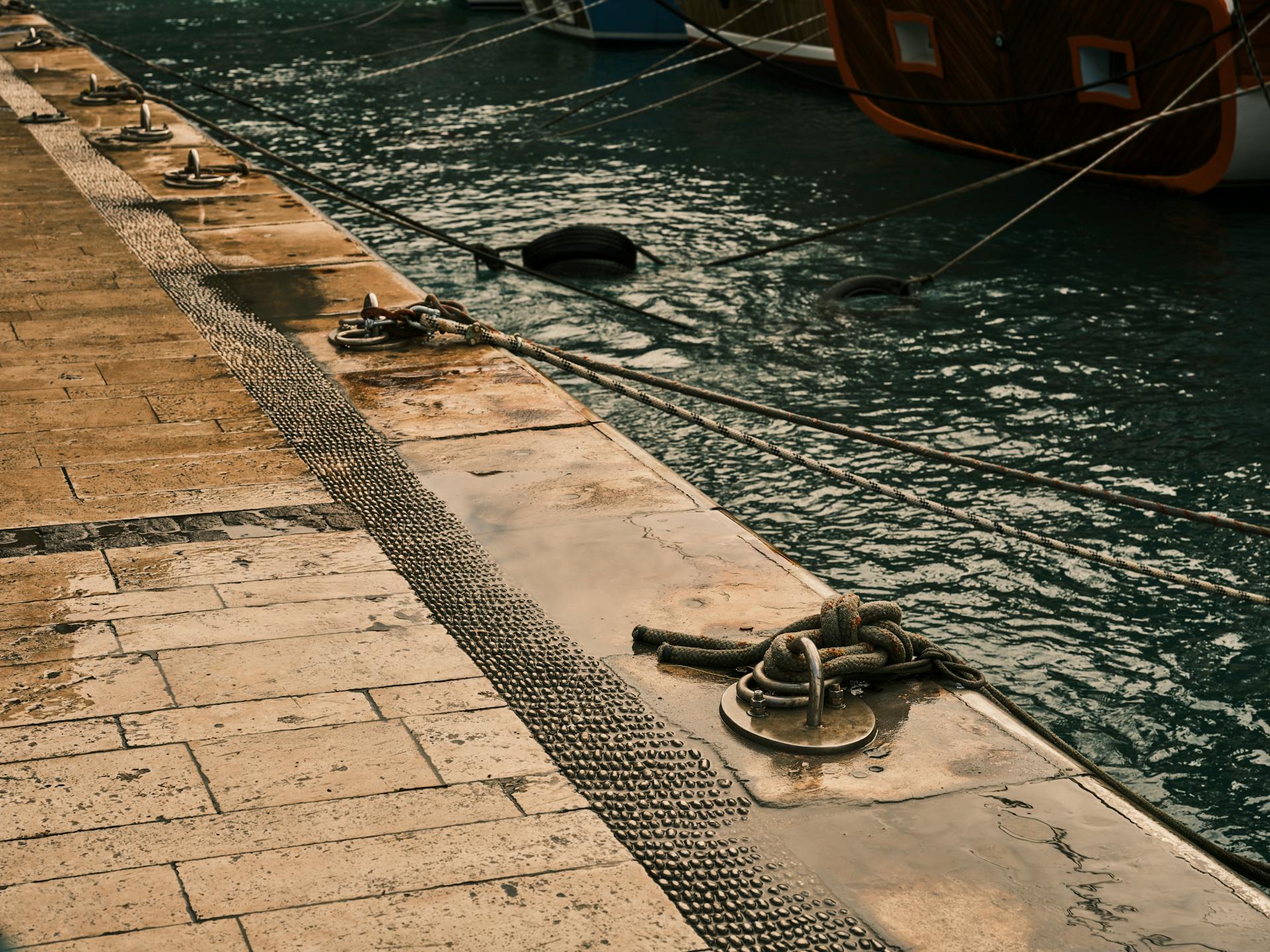 Dockside marina with ropes and docked boats, offering a serene maritime atmosphere.