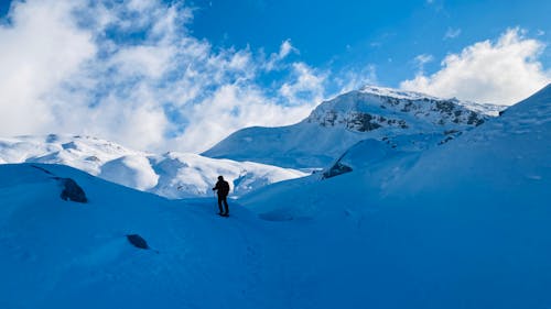 A Person in Black Jacket Standing on Snow Covered Mountain 