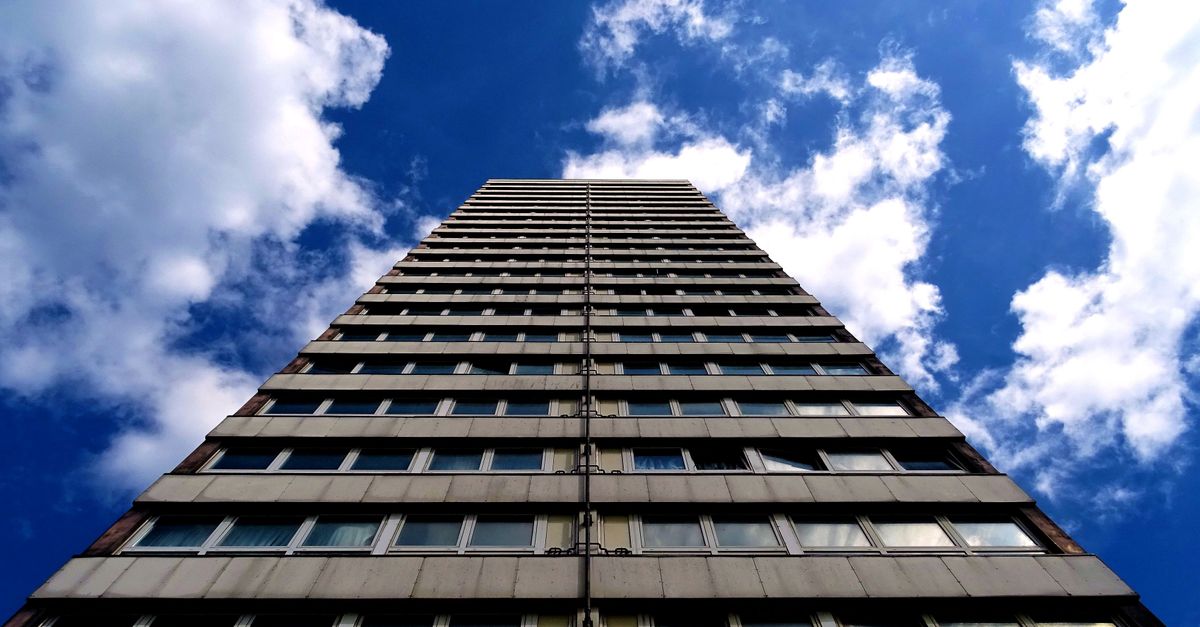 Low angle view of a modern skyscraper reaching into a clear, blue sky with clouds.