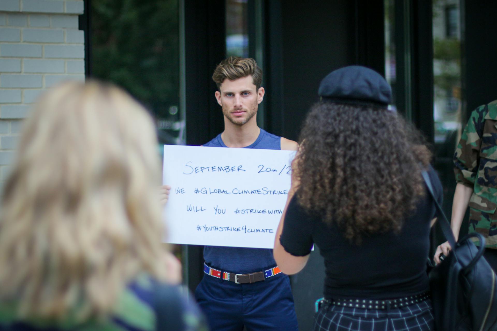 Young man holding a sign at a climate strike protest outdoors.