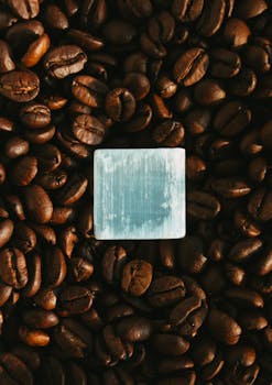 Flat lay of coffee beans surrounding an ice cube with a unique artistic effect.