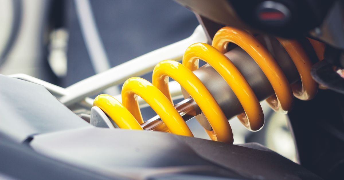Close-up of a vibrant yellow coil spring, showcasing mechanical engineering details.