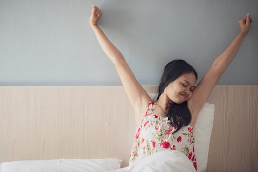 A woman joyfully stretching her arms while waking up in bed, feeling refreshed and energized.