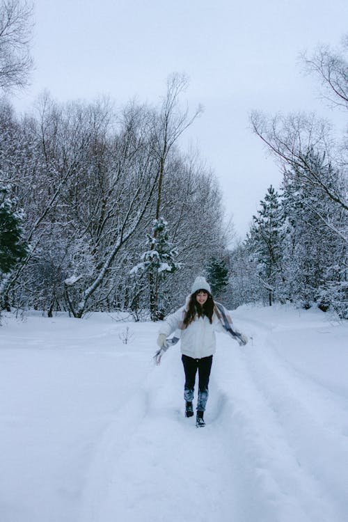 A Woman in a White Jacket Walking on the Snow-Covered Ground