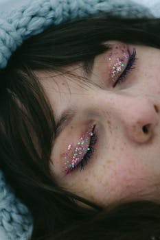 Close-up portrait of a woman with glitter eyeshadow and closed eyes.