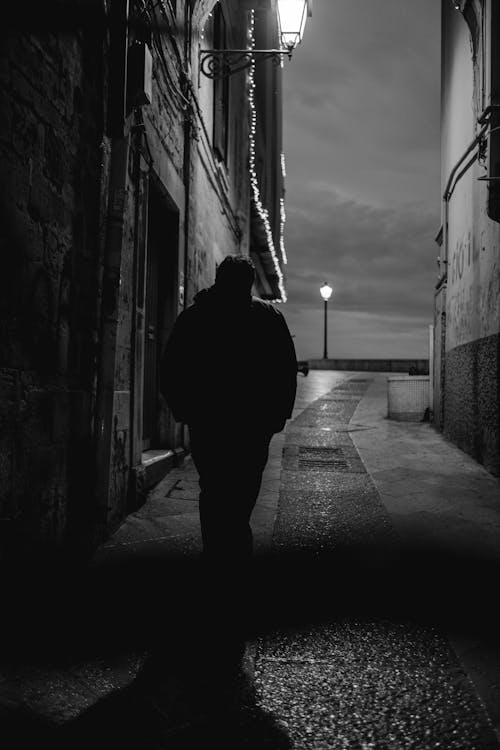 Grayscale Photo of a Man Walking on the Street