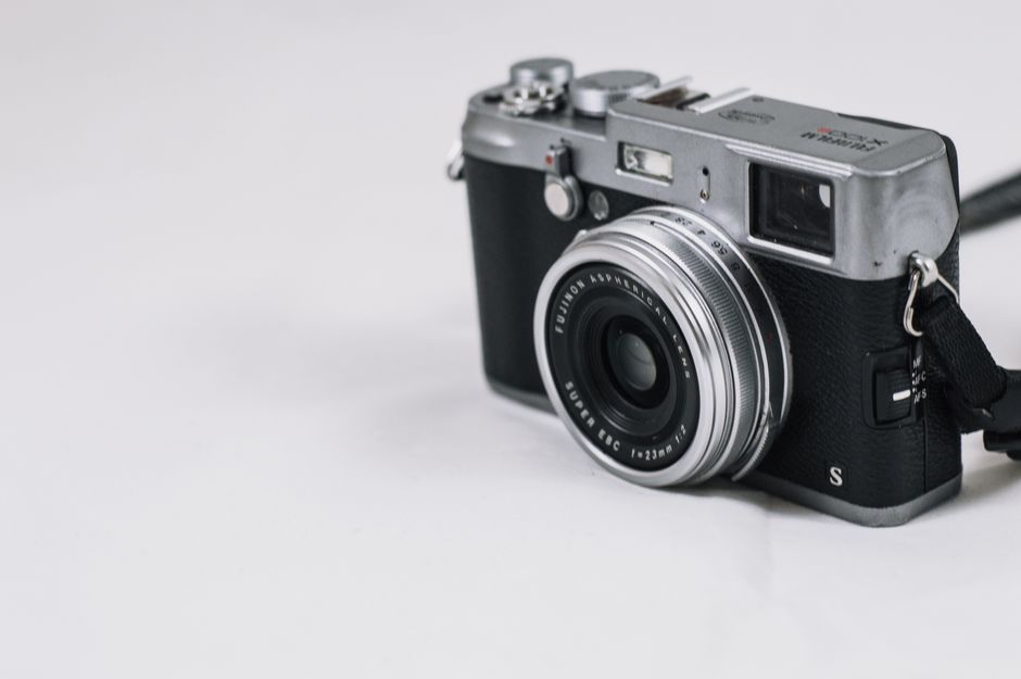 Close-up of a classic vintage rangefinder camera with a retro design on a plain background.