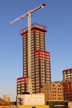 A tall skyscraper under construction with a crane during daytime.