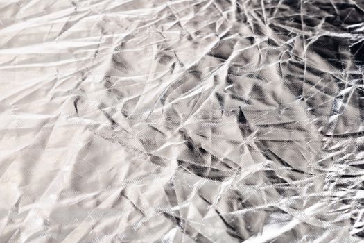 Detailed close-up of a crumpled silver surface showcasing unique textures and reflections.