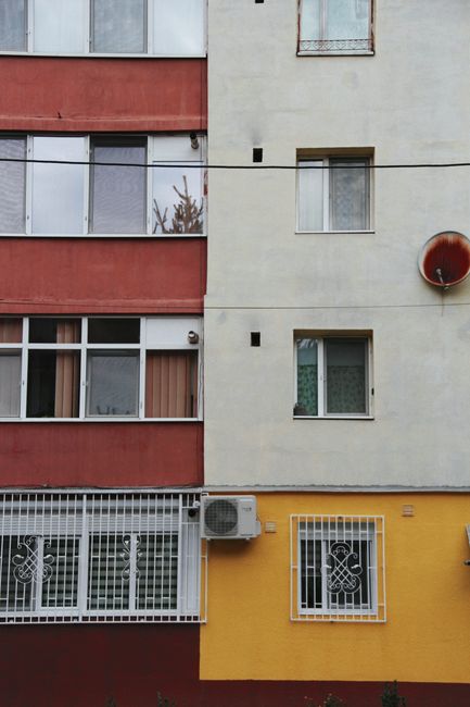 Vibrant apartment facade in urban Resita, Romania featuring diverse colors and textures.