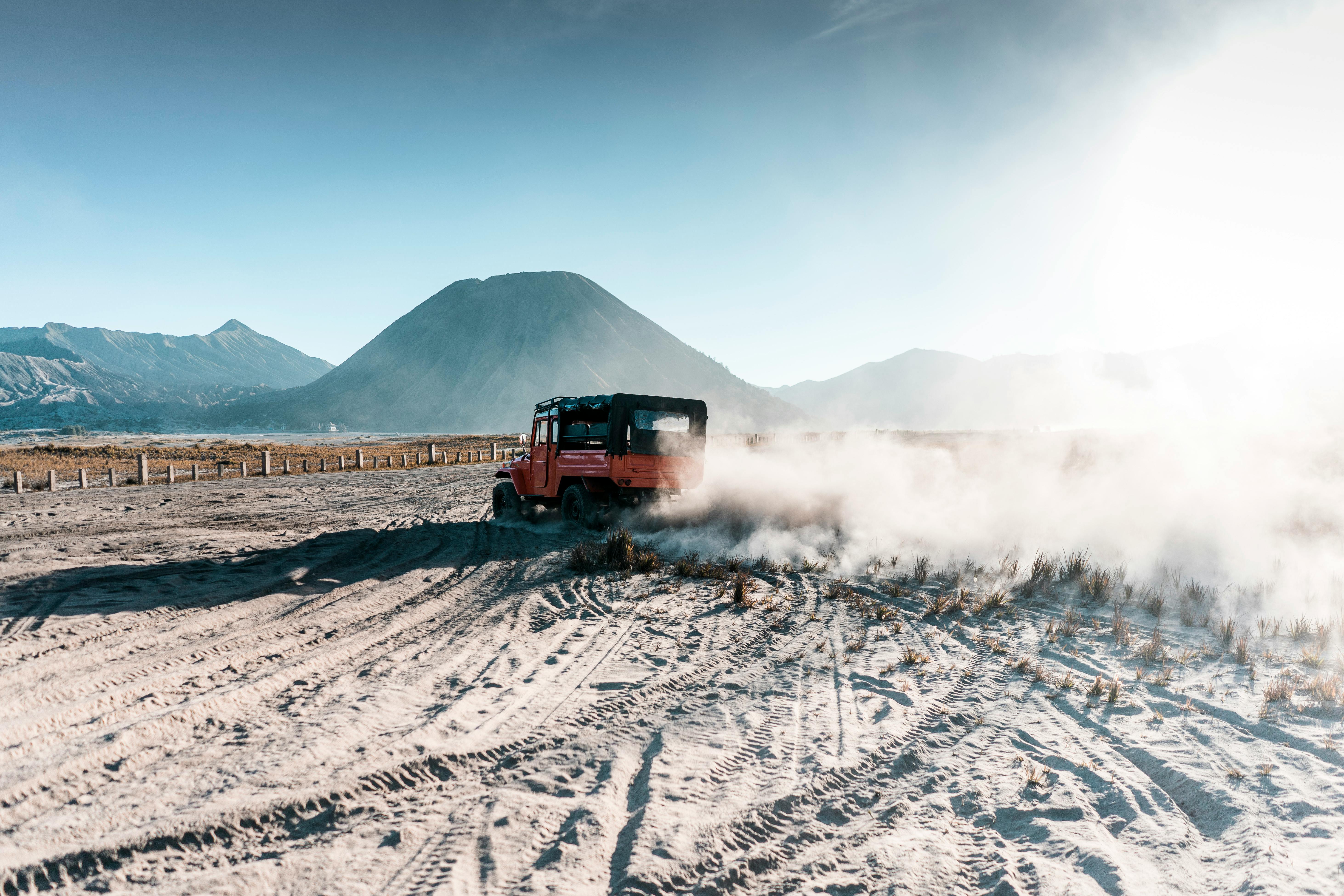 Off-road vehicle drives on sandy trails near Mount Bromo, Indonesia's iconic volcanic landscape.