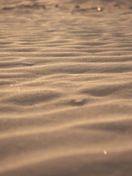 Close-up of dry sand with golden hues, creating a serene and textured pattern.