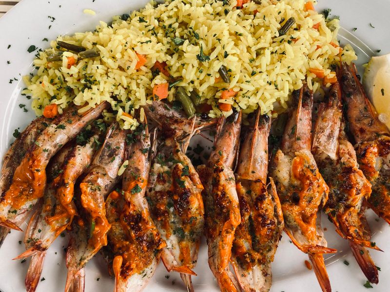 Delicious grilled prawns served with flavorful spiced rice on a plate.
