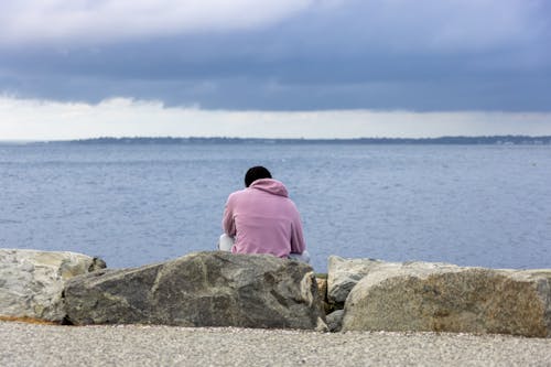 A Man in a Hoodie Sitting on a Rock