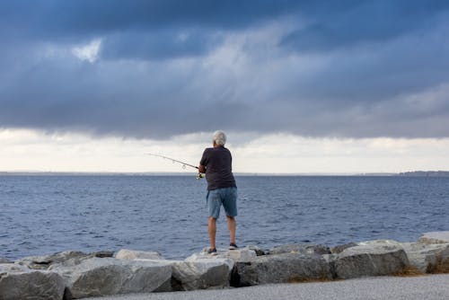 A Person in Black T-shirt and Denim Shorts Fishing on Sea
