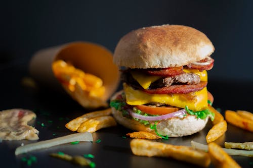 A Beef Burger with Fries Scattered on the Side