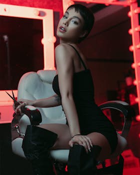 Sophisticated portrait of a woman in a black dress, seated elegantly in a studio setting.