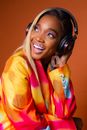 Woman in Orange Jacket Wearing Black Headphones